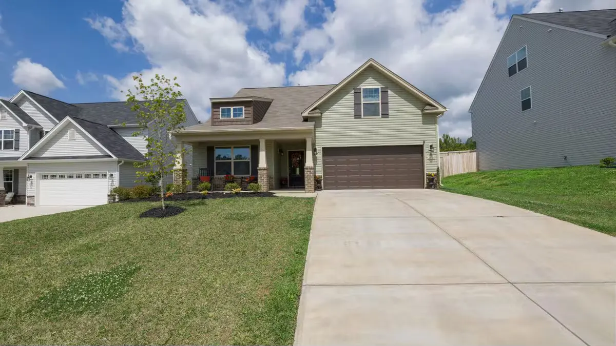 A modern suburban detached house with a spacious driveway under a bright blue sky.